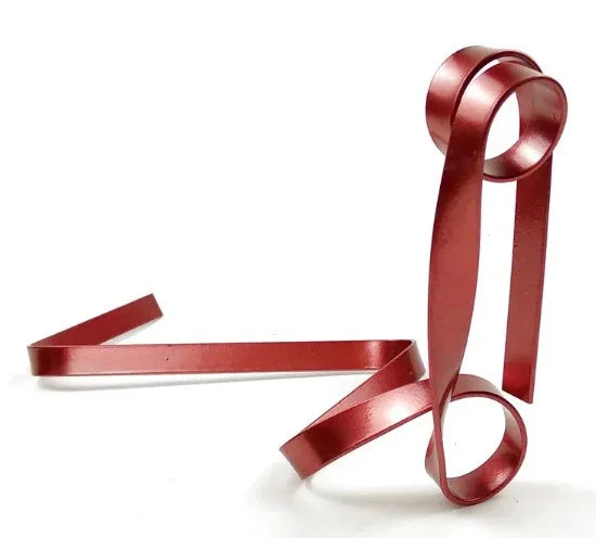 Abstract red metal sculpture with curled ribbon-like shapes on white background