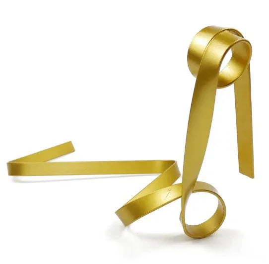 Modern gold metal tabletop sculpture with abstract ribbon design on white background
